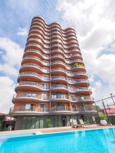 een hoog gebouw met een zwembad ervoor bij Intimate Studio Apartment - Mirage Residence in Accra