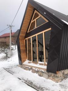 a small house with a black roof in the snow at Chalet Wood Magic in Kolašin