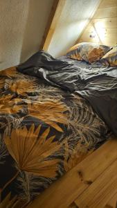 an unmade bed with a comforter with leaves on it at Chalet Wood Magic in Kolašin
