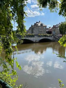 a bridge over a river with buildings and trees at Les Maisons d'Auré in Putanges +10 photos