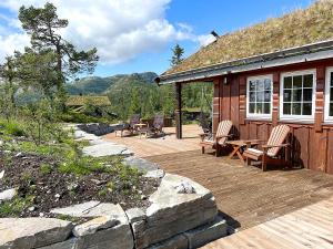 une terrasse en bois avec des chaises et une maison avec un toit dans l'établissement Cozy cabin on Lifjell with jacuzzi close to cross-country trails and hiking trails, à Lifjell