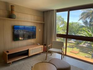 a living room with a table and a chair and a large window at Guarajuba Suítes Premium Boutique Hotel in Guarajuba