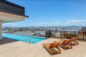 a balcony with chairs and a swimming pool on a building at Wi-FIi | 250MB | Sea View | Pool #CA60 in Florianópolis