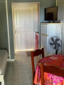 eine Küche mit einem Kühlschrank, einem Tisch und einer Tür in der Unterkunft Gîte Allée des Cocotiers in Saint-François