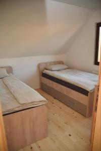 two beds in a small room with wooden floors at Planinska kuća Srna in Bajina Bašta