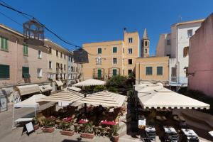 um café ao ar livre com guarda-sóis e mesas brancas em Casa dei Liuti em Alghero