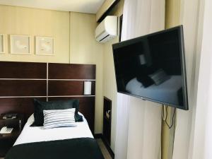 a bedroom with a bed with a large television on the wall at Delicioso flat em área nobre in Sao Paulo