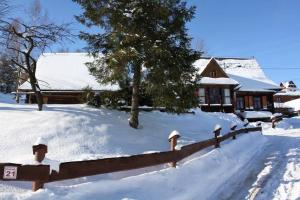 pokryty śniegiem dziedziniec z ogrodzeniem i domem w obiekcie DZIUPLA - Berghaus in der Tatra mit Holzsauna w mieście Brzegi