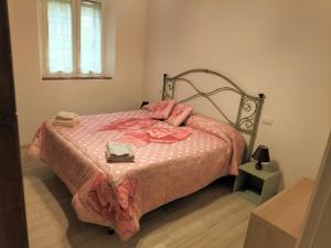 a bedroom with a bed with pink sheets and a window at House of terme bilocale a due passi dalle terme di rapolano in Rapolano Terme