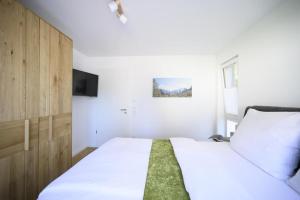 a bedroom with a large white bed and a tv at Ferienwohnung Am Kofel in Oberammergau