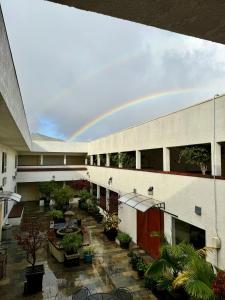 a rainbow over a building with a courtyard with plants at Airport Inn in South San Francisco