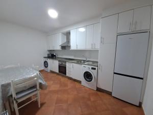 uma cozinha com armários brancos e uma máquina de lavar e secar roupa em Galitrips Casa Corneta em Cangas