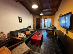 a living room with a black leather couch and a table at Casa hasta 11 personas in Necochea