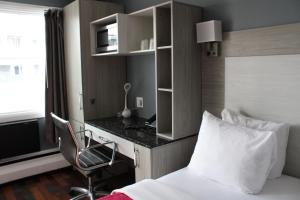 Olux Hotel-Motel-Suites في لافال: غرفة في الفندق بسرير وكرسي ومكتب