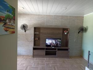 a living room with a tv and a brick wall at Duplex Praia dourada in Maragogi