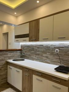 a kitchen with white cabinets and a sink at Surčin Centar apartment in Surčin +28 photos
