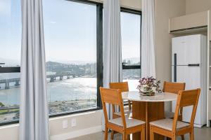 a kitchen with a table and chairs and a large window at Wi-Fi 250MB | Sea View | Pool #CA61 in Florianópolis