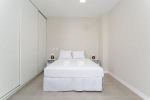 a white bedroom with a white bed and white walls at Wi-Fi 250MB | Sea View | Pool #CA61 in Florianópolis