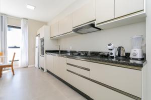 a kitchen with white cabinets and black counter tops at Wi-Fi 250MB | Sea View | Pool #CA61 in Florianópolis +50 photos