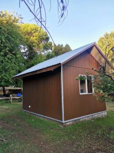 a brown building with a window in a yard at Refugio Kiñeco in Conguillio