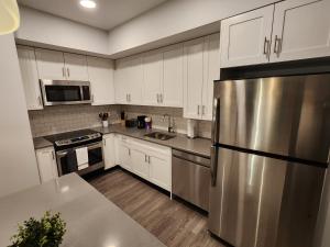 a kitchen with white cabinets and a stainless steel refrigerator at Astonishing 2BR Apt Mins to NYC in Jersey City