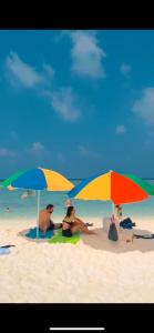 dos personas sentadas bajo sombrillas en una playa en Oceano Beach Vashafaru en Vashafaru