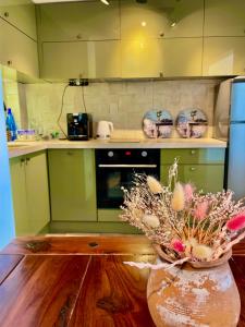 una cucina con armadi verdi e un vaso con fiori di Art Luxury Apartment - central, metro to airport a Sofia