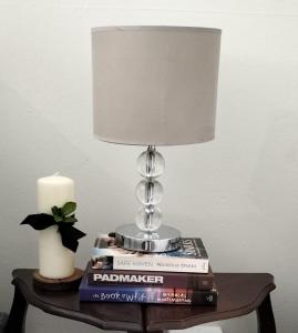 une lampe sur une table avec des livres et une bougie dans l'établissement Bly 'n Bietjie Ceres, à Ceres