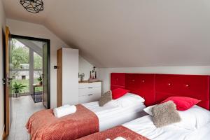 two beds with red headboards in a bedroom at Domy na Roztoczu Aleja Lipowa B,G,J,K Sauna Jacuzzi Kajaki in Zwierzyniec +74 photos