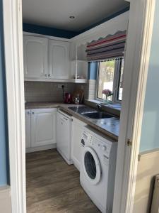 a kitchen with white cabinets and a washer and dryer at Rossnowlagh Beach House in Donegal