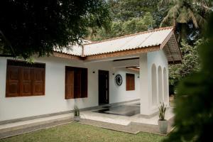 a white house with brown doors and a yard at Woradi Solitude Bungalow in Talpe