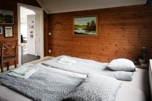 two beds in a bedroom with a wooden wall at Snickaren Vandrarhem i Grästorp - Egen Lägenhet - Own apartments in Grästorp