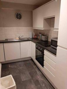a kitchen with white cabinets and black counter tops at Modern two bed flat in Canada Water close to transport in London