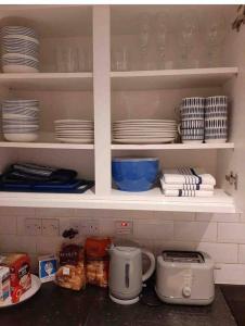 a kitchen shelf with plates and dishes on it at Modern two bed flat in Canada Water close to transport in London