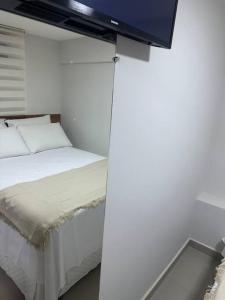 a bedroom with a bed with a tv on the wall at Apto 16 lindo e confortável in Montes Claros