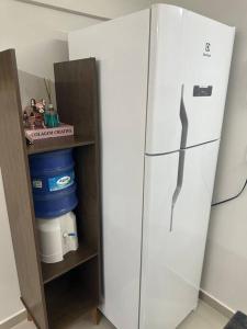 a white refrigerator sitting in a kitchen next to a shelf at Apto 16 lindo e confortável in Montes Claros