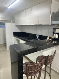 a kitchen with a counter and two chairs in it at Apto 16 lindo e confortável in Montes Claros