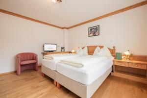 1 dormitorio con 2 camas blancas y escritorio en Biohotel Leutascherhof, en Leutasch