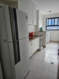 a kitchen with white cabinets and a large refrigerator at BEACH FLAT in Salvador