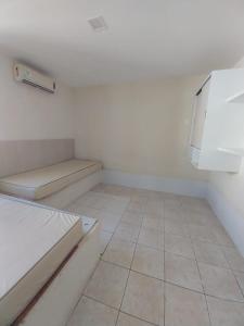 Habitación blanca pequeña con cama y suelo de baldosa. en Flats Temporada & Mensal, en Aracaju