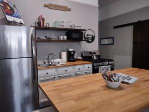 eine Küche mit einem Kühlschrank aus Edelstahl und einem Holztisch in der Unterkunft 2feathers inn in Natchez