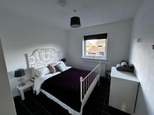 a white bedroom with a bed and a window at The Eves in Corbridge