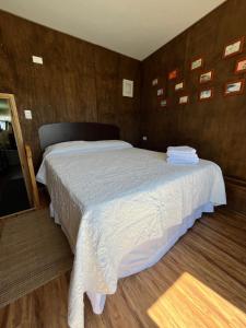 a bedroom with a large bed with white sheets at Cabaña Náutica in Puerto Natales