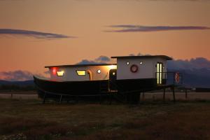 a boat sitting in a field with the sunset in the background at Cabaña Náutica in Puerto Natales
