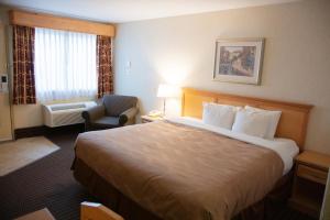 a hotel room with a large bed and a chair at All Stay Suites in Westlock