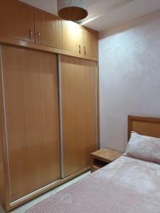 a bedroom with a bed and some wooden cabinets at Al-Nasr in Agadir