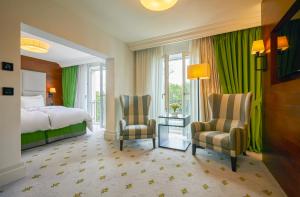 a bedroom with a bed and two chairs in a room at Kempinski Hotel Frankfurt Gravenbruch in Gravenbruch