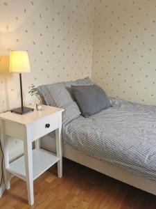 een slaapkamer met een bed en een nachtkastje met een lamp bij Gästhus nära havet in Kalmar