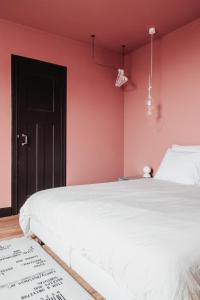 1 dormitorio con cama blanca y pared rosa en Huis Hector Mechiels, en Sint-Niklaas