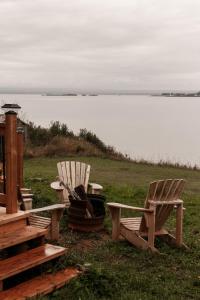 two chairs and a bench next to a body of water at Le Martin Pecheur 2 chambres in Nouvelle